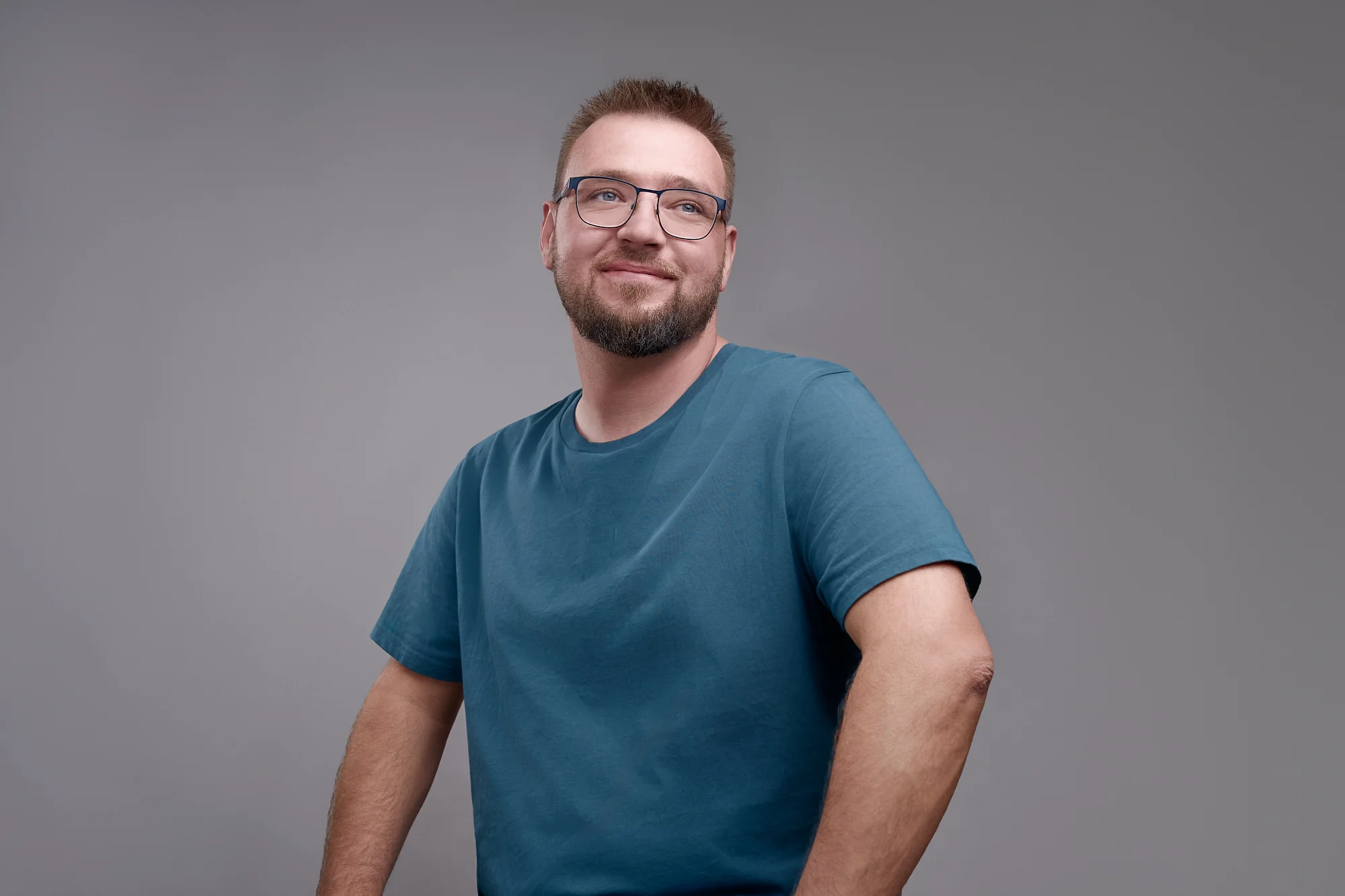 Paul Böstro im blauen Shirt vor grauem Hintergrund, er lächelt