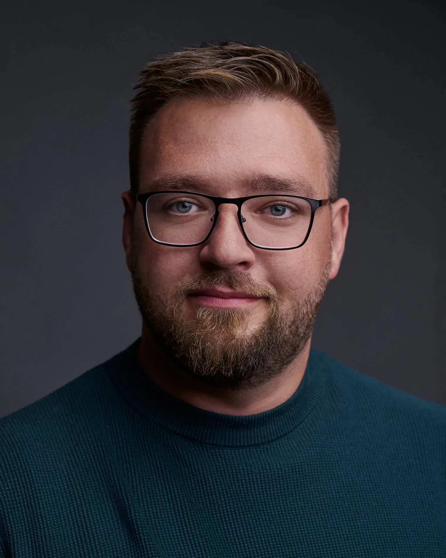 Porträt von Paul Böstro im dunklen Pullover vor dunklem Hintergrund