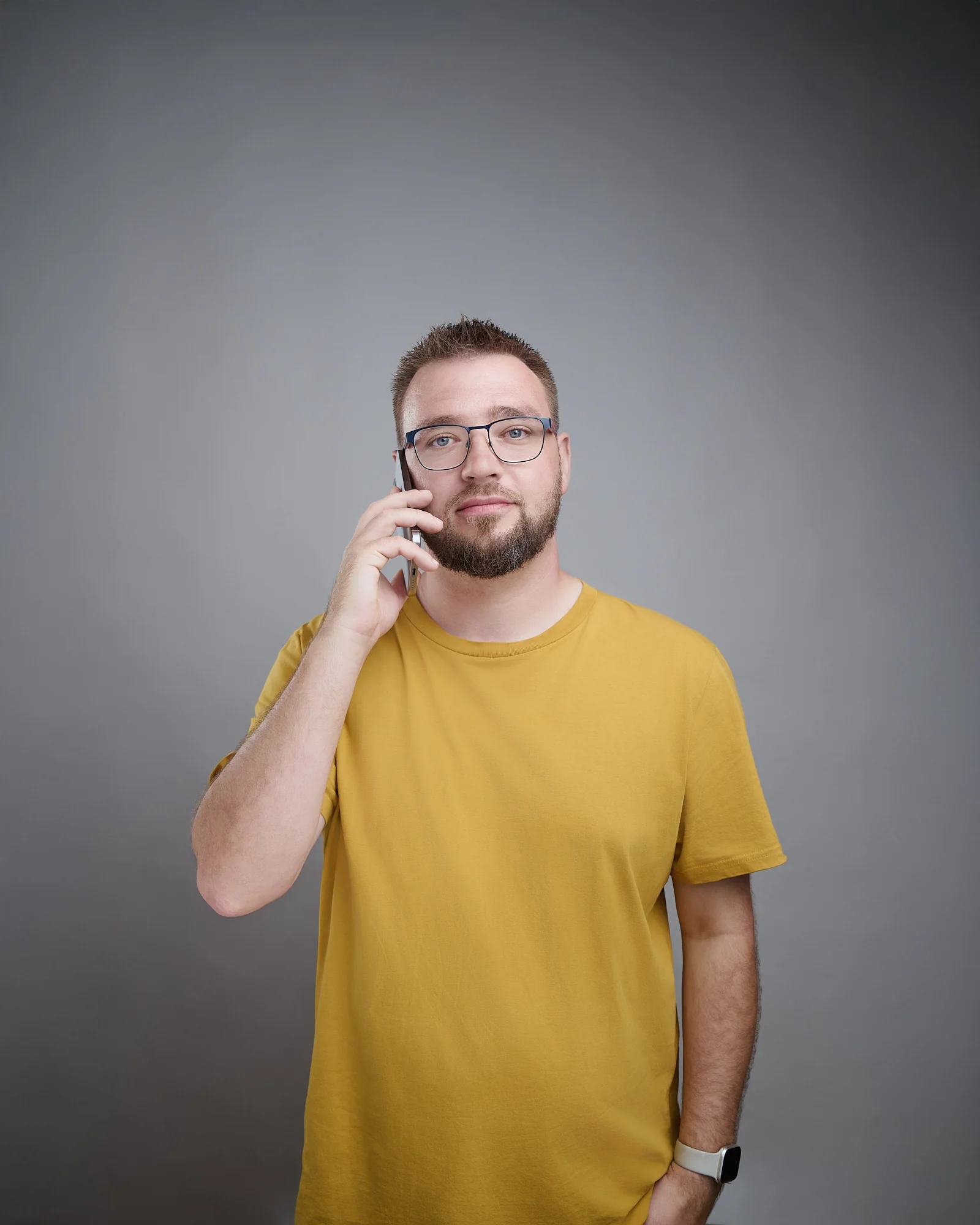 Paul Böstro im gelben Shirt telefoniert, grauer Hintergrund