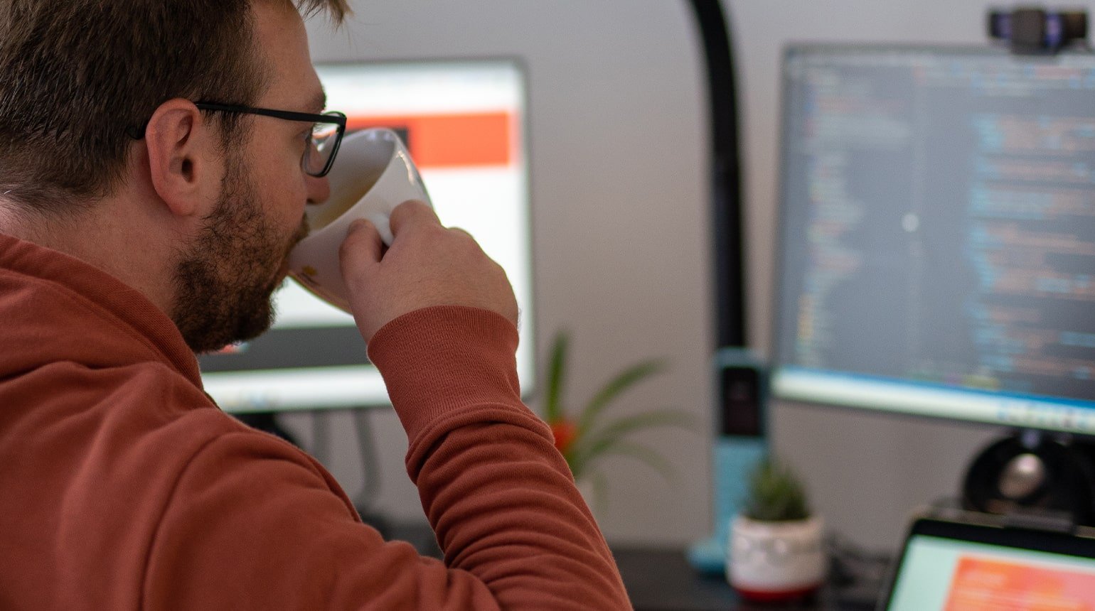 Paul Böstro von creativecouch arbeitet am Schreibtisch mit Code auf zwei Monitoren