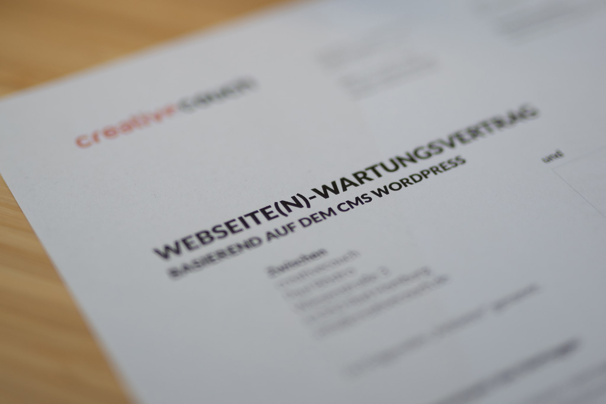 Nahaufnahme eines Dokuments mit dem Titel "WEBSEITE(N)-WARTUNGSVERTRAG" auf einem Schreibtisch.