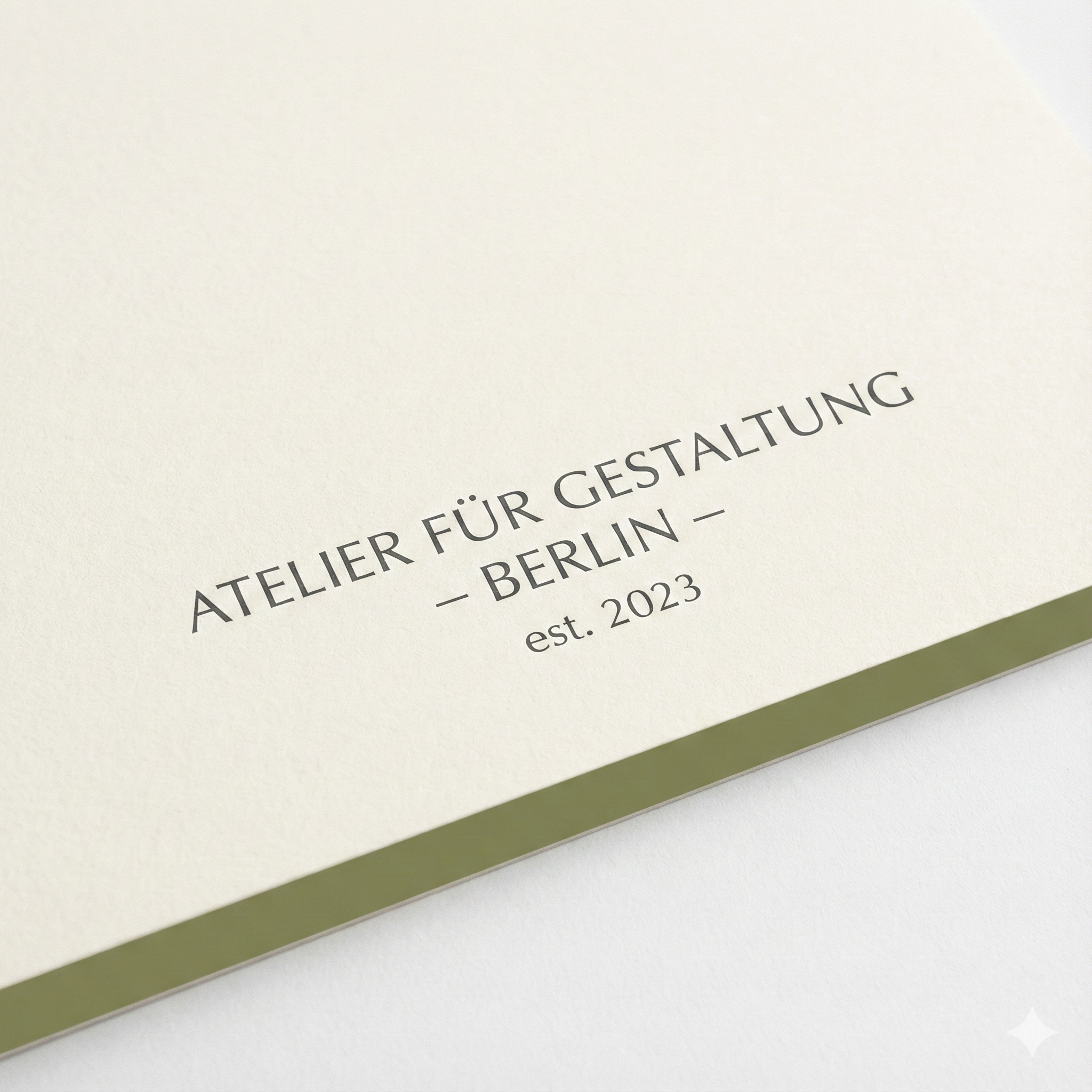 Nahaufnahme einer cremefarbenen Karte mit dem Text "ATELIER FÜR GESTALTUNG - BERLIN - est. 2023" im minimalistischen Stil.